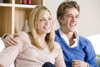 Young Couple Sitting On Sofa Together Watching TV