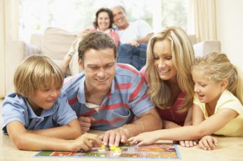 Family Playing Board Game At Home With Grandparents Watching