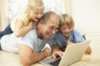 Grandfather AndGrandchildren Using Laptop At Home