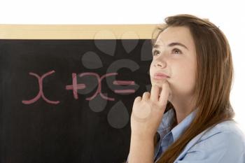 Thoughtful Looking Female Student Standing Next To Blackboard