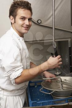 Kitchen Worker Washing Up In Restaurant Kitchen