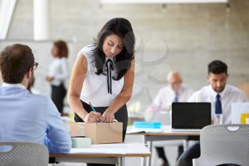 Businesswoman In Office Addressing Package For Shipping