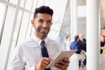 Hispanic Businessman Using Digital Tablet In Modern Office