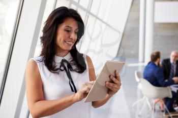 Hispanic Businesswoman Using Digital Tablet In Modern Office