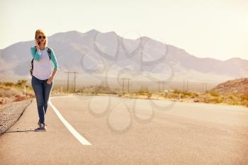 Woman On Vacation Hitchhiking Along Road Using Mobile Phone