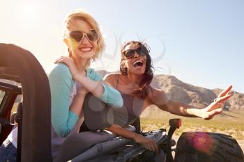Two Female Friends On Road Trip In Back Of Convertible Car