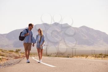 Couple On Vacation Hitchhiking Along Road