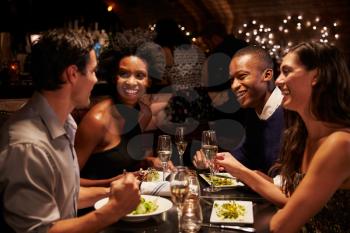 Two Couples Enjoying Meal In Restaurant Together