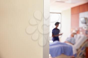 Focus On Hospital Room Sign With Nurse Talking To Patient