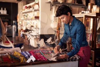 Female Sales Assistant Arranging Textiles In Homeware Store