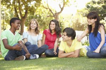 Group Of Teenagers Chatting Together In Park
