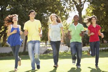 Group Of Teenagers Running Through Park