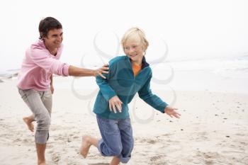 Father Chasing Son Along Winter Beach