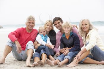 Three Generation Family Sitting On Winter Beach Together