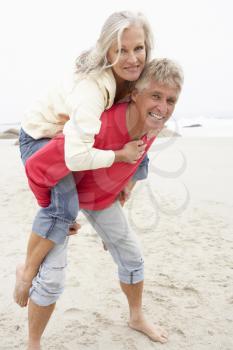 Senior Man Giving Woman Piggyback On Winter Beach