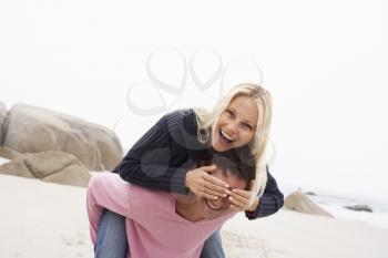 Man Giving Woman Piggyback On Winter Beach