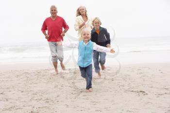 Grandparents And Grandchildren Running On Winter Beach Together