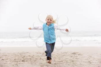 Young Girl On Holiday Running Along Winter Beach