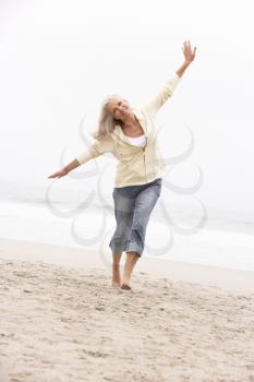 Senior Woman On Holiday Running Along Winter Beach