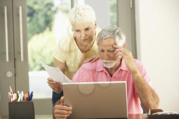 Worried Senior Couple Using Laptop At Home
