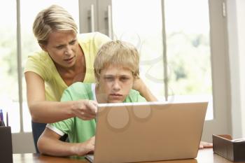 Angry Mother And Teenage Son Using Laptop At Home