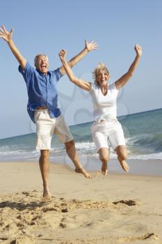 Senior Couple Enjoying Beach Holiday Jumping In Air
