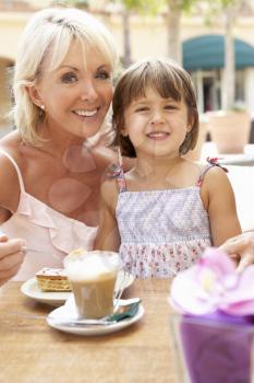 Grandmother With Granddaughter Enjoying Coffee And Cake In Caf
