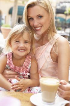 Mother And Daughter Enjoying Cup Of Coffee And Piece Of Cake In Caf
