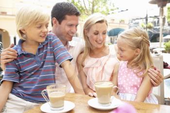 Young Family Enjoying Cup Of Coffee In Caf Together