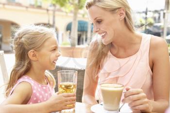 Mother And Daughter Enjoying Cup Of Coffee And Juice In Caf Together