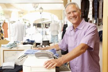 Male Sales Assistant At Checkout Of Clothing Store