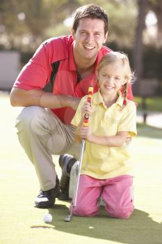 Father Teaching Daughter To Play Golf On Putting On Green