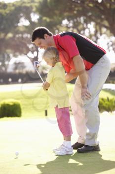 Father Teaching Daughter To Play Golf On Putting On Green