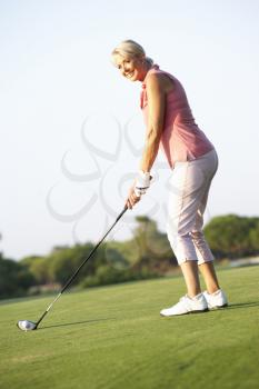 Senior Female Golfer Teeing Off On Golf Course
