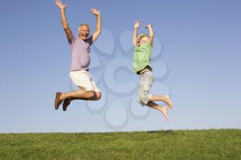 Senior man with grandson jumping in air