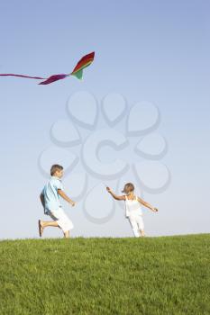 Young children run with kite through field