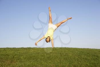 Young woman cartwheels in field