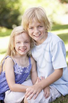 Brother and sister pose in a park