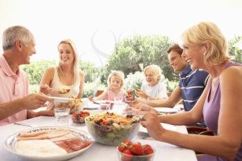 Extended family, parents, grandparents and children, eating outdoors