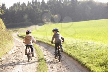 Two young children ride bicycles in park