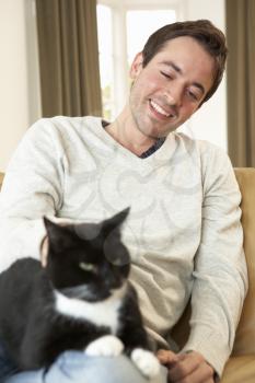 Happy young man with cat sitting on sofa