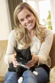 Happy young woman with cat sitting on sofa