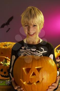 Halloween party with a boy holding carved pumpkin