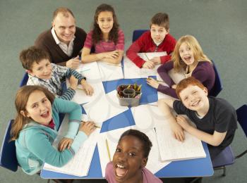 Overhead View Of Schoolchildren Working Together At Desk With Teacher