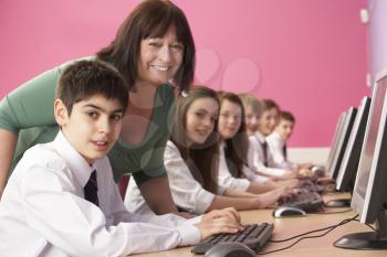 Teenage Students In IT Class Using Computers In Classroom With Tutor