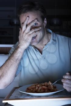 Frightened Man Enjoying Meal Whilst Watching TV