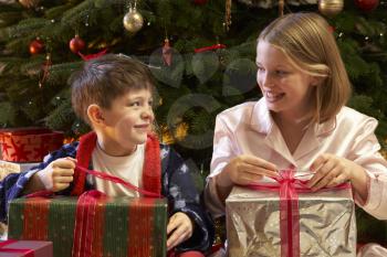 Children Opening Christmas Present In Front Of Tree