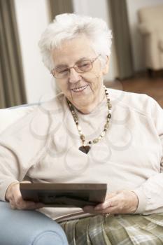 Senior Woman Looking At Photograph In Frame