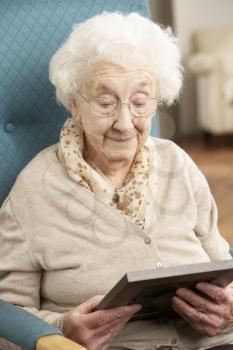 Sad Senior Woman Looking At Photograph In Frame