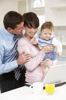 Parents With Baby Working From Home Using Laptop